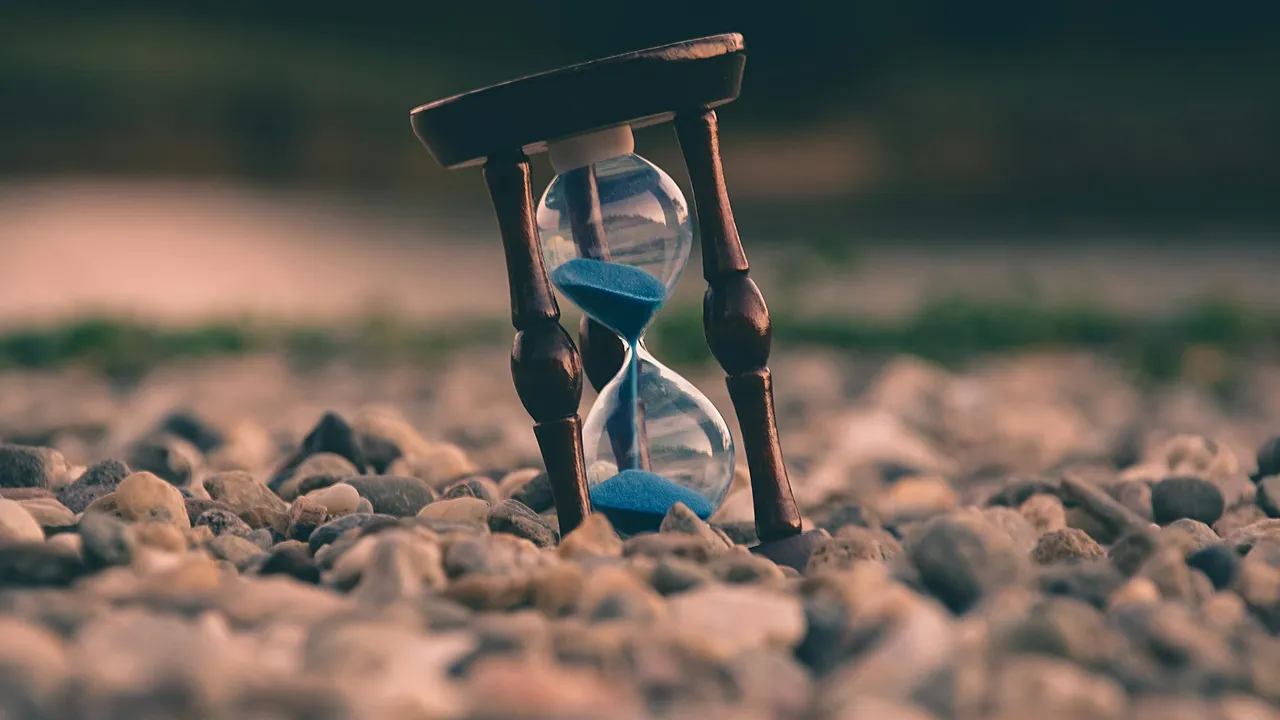 An hourglass with blue sand running through it, marking the passage of time