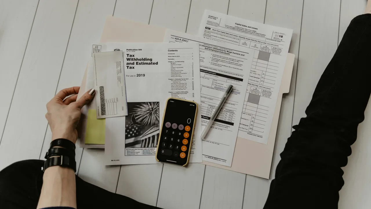 A calculator resting on financial and tax documents while someone plans a budget