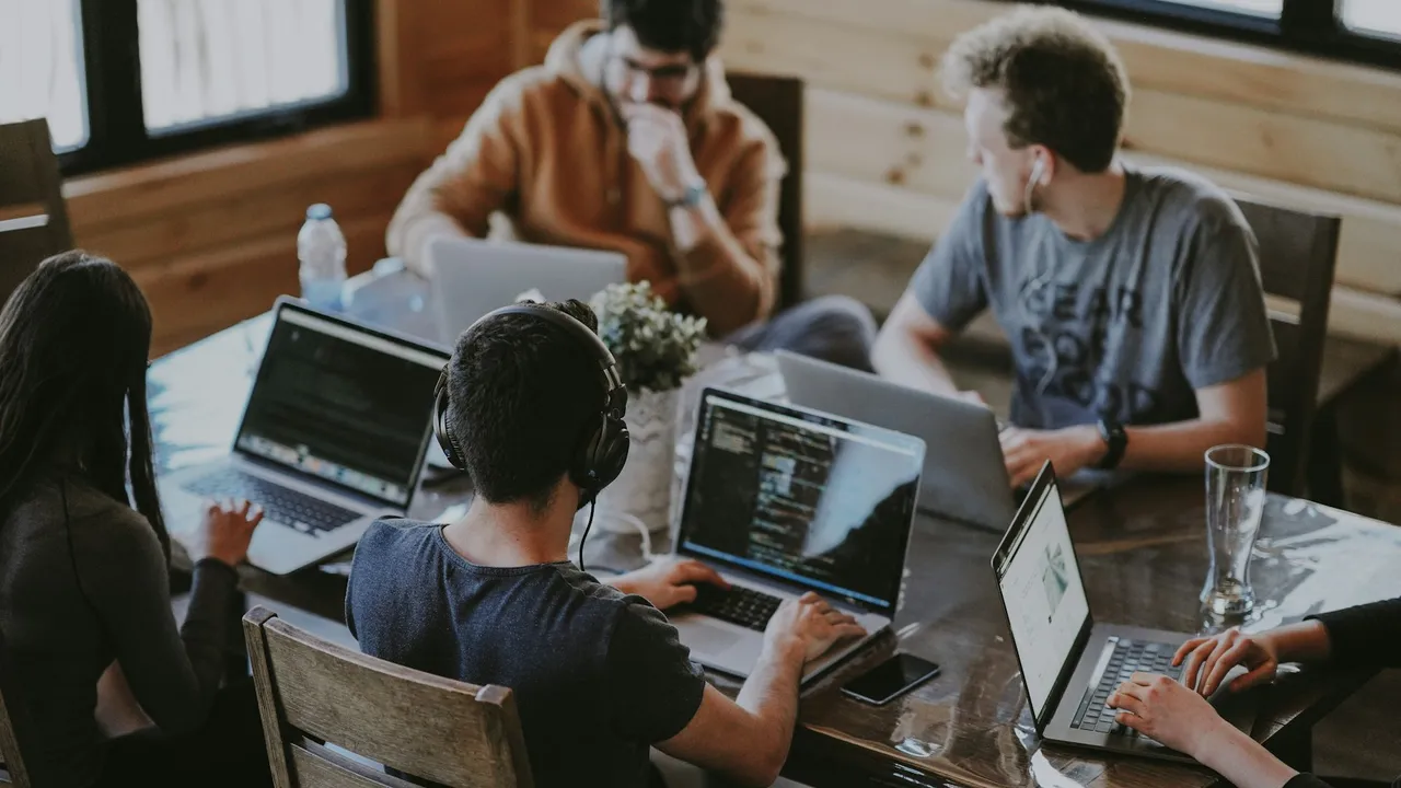 A web design team working together on laptops around a wooden table