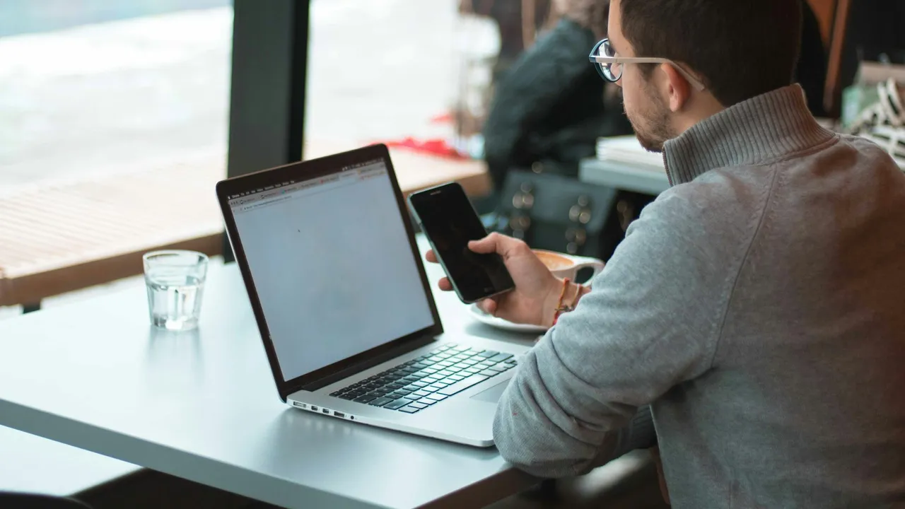 A person working alone at a desk with a laptop by a window