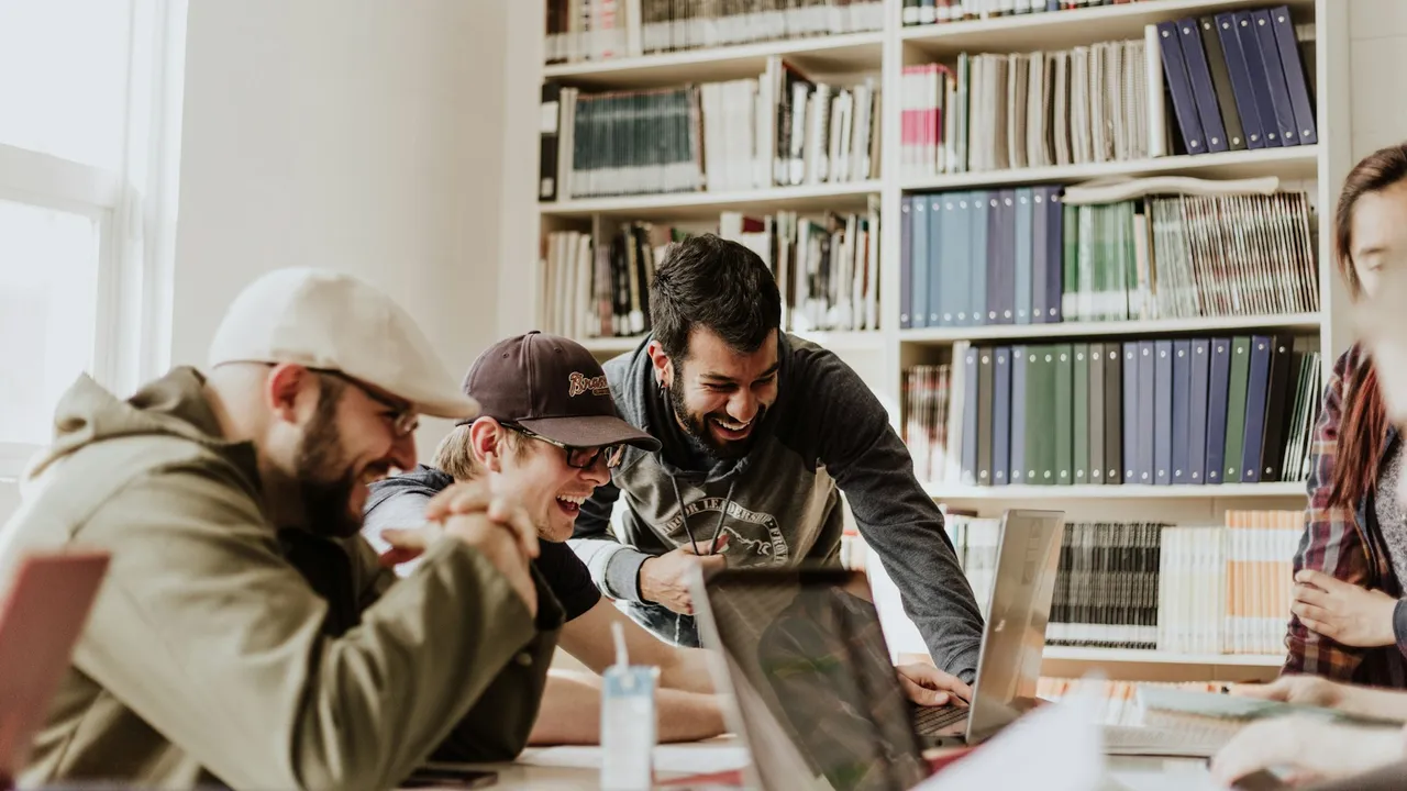 A small team laughing together over a laptop while weighing a decision